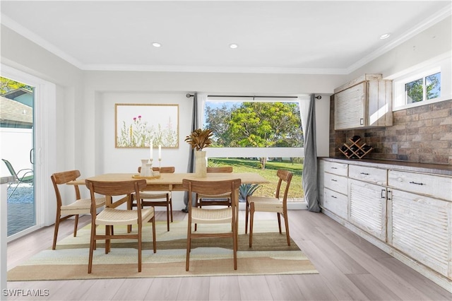 dining space with light wood-type flooring and ornamental molding