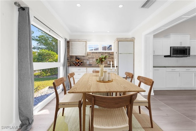 dining area with crown molding and light hardwood / wood-style floors