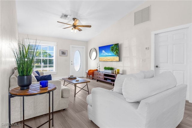 living room with ceiling fan, vaulted ceiling, and light wood-type flooring