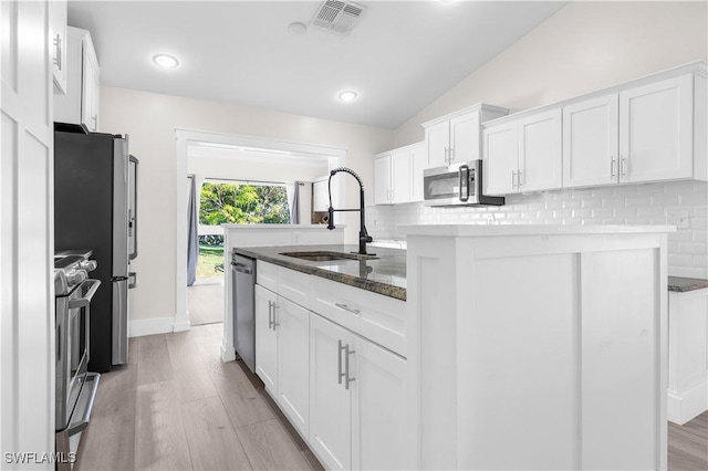 kitchen with white cabinetry, sink, vaulted ceiling, decorative backsplash, and appliances with stainless steel finishes