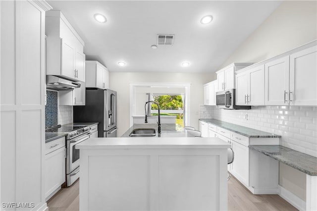 kitchen with white cabinets, sink, appliances with stainless steel finishes, and an island with sink