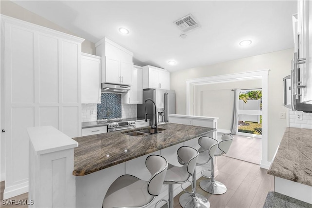 kitchen featuring white cabinets, a center island with sink, sink, light hardwood / wood-style flooring, and stainless steel appliances