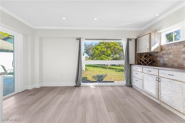 unfurnished dining area with light wood-type flooring, ornamental molding, and a wealth of natural light