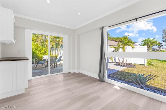 unfurnished dining area with light wood-type flooring and crown molding