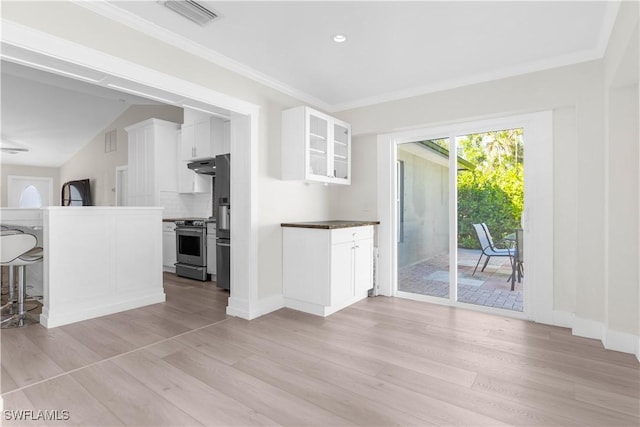 kitchen with white cabinetry, light hardwood / wood-style flooring, lofted ceiling, decorative backsplash, and appliances with stainless steel finishes