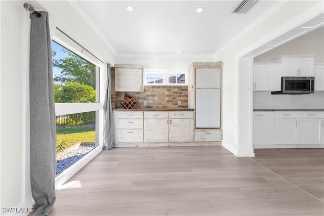 kitchen with backsplash, light hardwood / wood-style flooring, a wealth of natural light, and crown molding