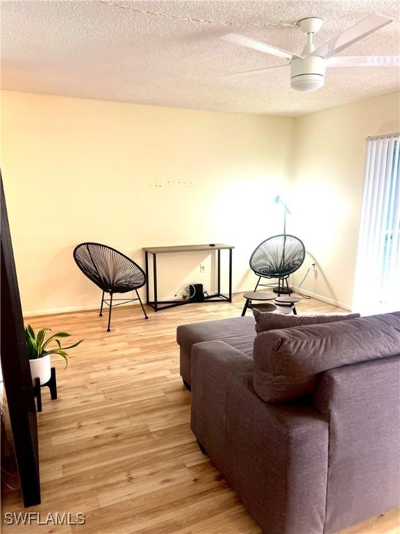 sitting room featuring ceiling fan, light hardwood / wood-style floors, and a textured ceiling