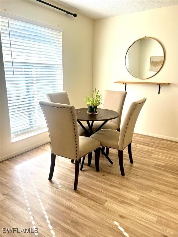 dining area featuring a textured ceiling and light hardwood / wood-style flooring