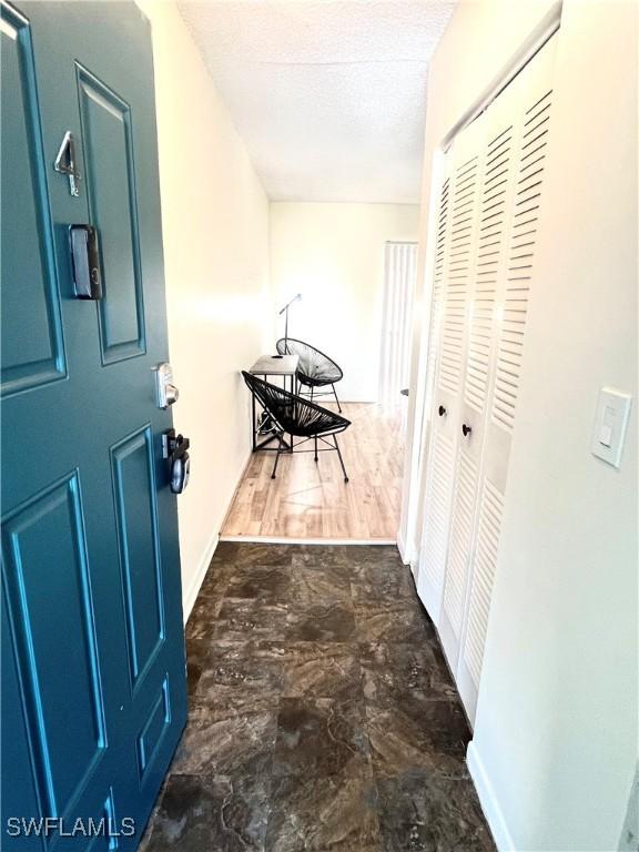 corridor with a textured ceiling and dark hardwood / wood-style floors