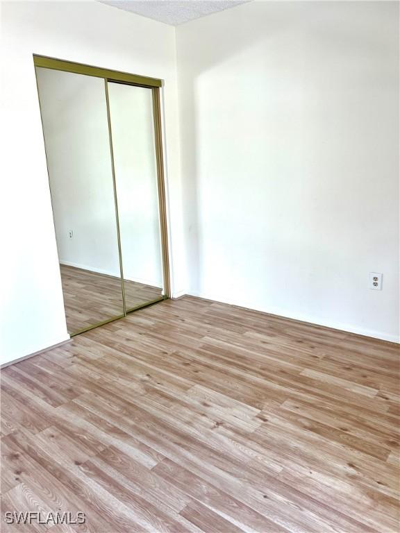 unfurnished bedroom with a textured ceiling, light hardwood / wood-style floors, and a closet