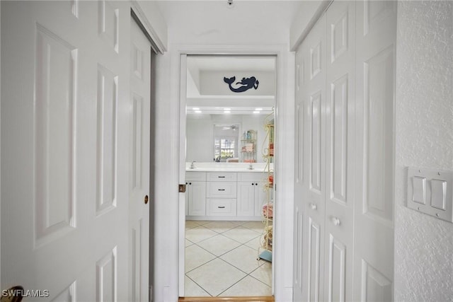 corridor with light tile patterned floors and sink