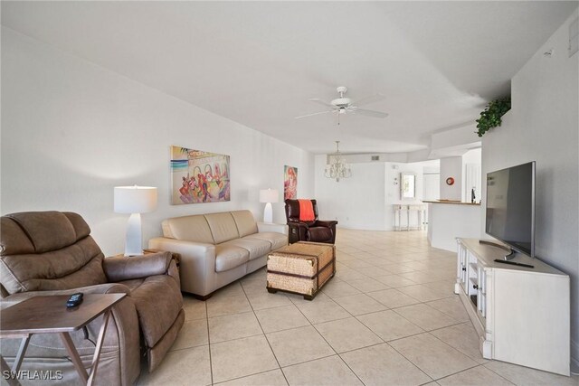 tiled living room with ceiling fan with notable chandelier