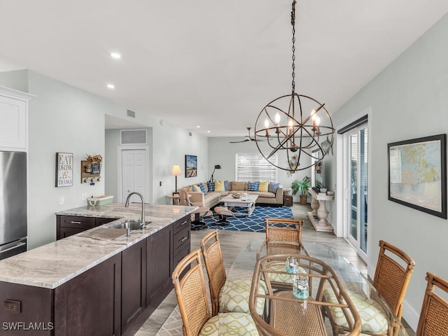 dining area featuring a notable chandelier, light wood-type flooring, and sink