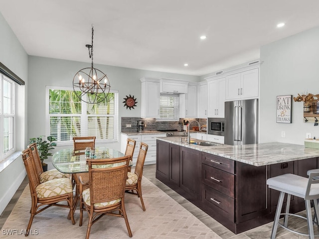 kitchen with white cabinets, a notable chandelier, light stone counters, and appliances with stainless steel finishes