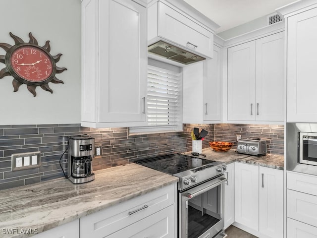 kitchen with light stone countertops, backsplash, stainless steel appliances, and white cabinetry