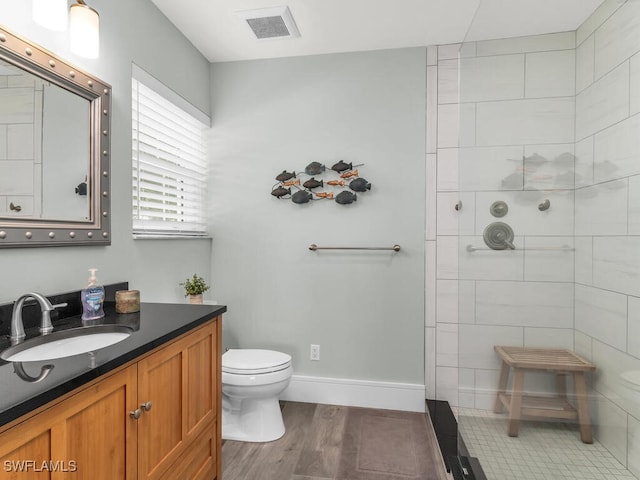 bathroom featuring tiled shower, toilet, vanity, and hardwood / wood-style flooring