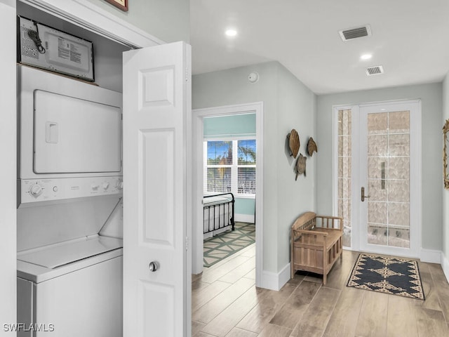 laundry room with wood-type flooring and stacked washer and clothes dryer