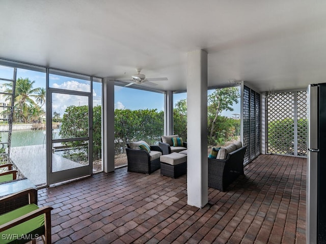 sunroom featuring ceiling fan and a water view