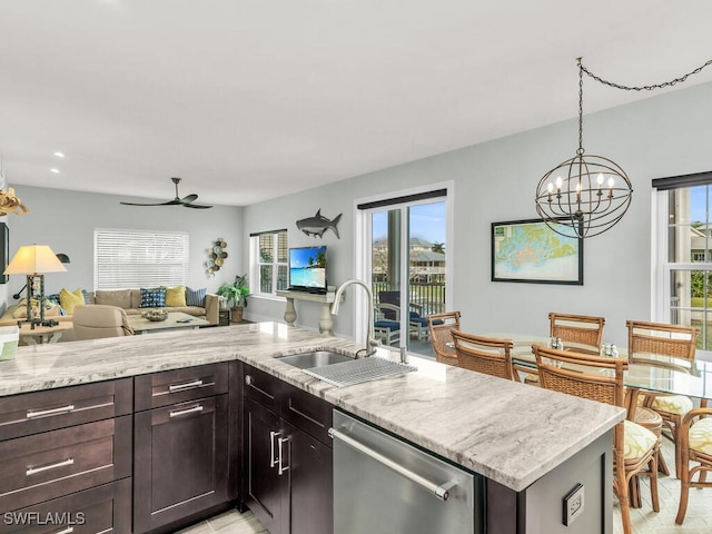 kitchen featuring dishwasher, ceiling fan with notable chandelier, sink, dark brown cabinets, and light stone counters