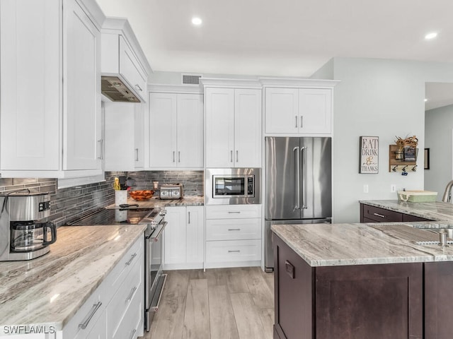 kitchen with stainless steel appliances, light stone counters, light hardwood / wood-style flooring, decorative backsplash, and white cabinets