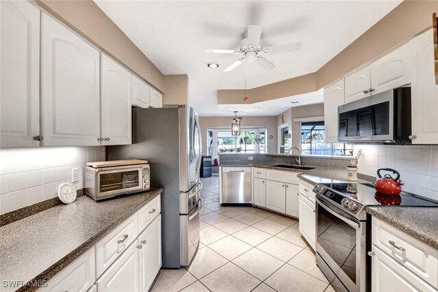 kitchen with appliances with stainless steel finishes, tasteful backsplash, ceiling fan, sink, and white cabinetry