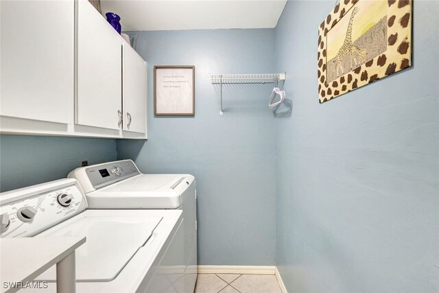 laundry room featuring cabinets, light tile patterned floors, and washing machine and dryer