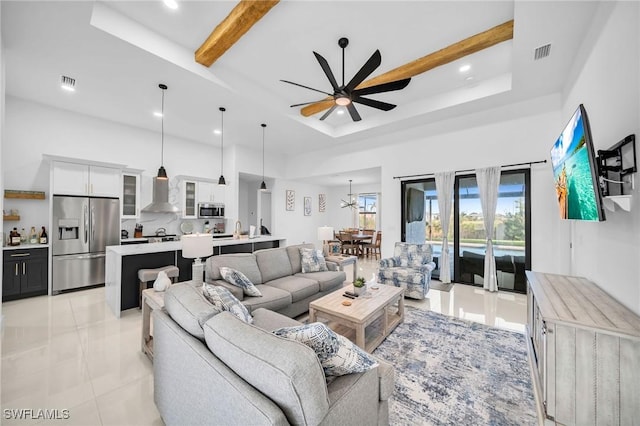 living room with beamed ceiling, ceiling fan, a raised ceiling, and light tile patterned floors