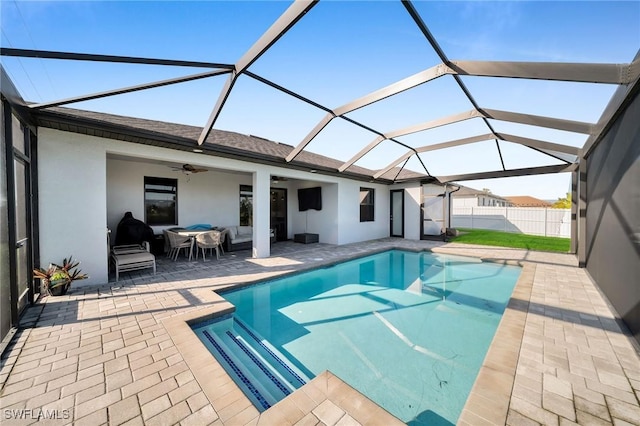 view of swimming pool with glass enclosure, a patio area, and ceiling fan