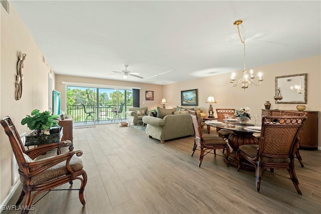 dining area with hardwood / wood-style flooring and ceiling fan with notable chandelier