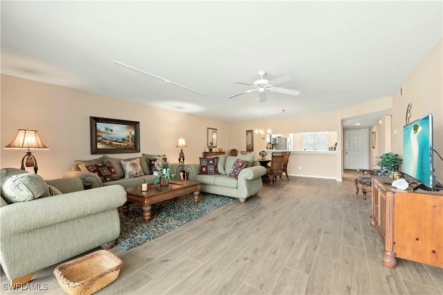 living room featuring light hardwood / wood-style floors and ceiling fan with notable chandelier