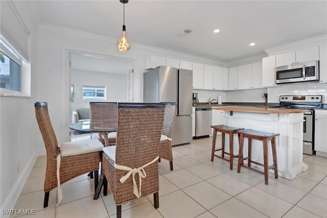 kitchen featuring tasteful backsplash, stainless steel appliances, a kitchen island, crown molding, and white cabinetry