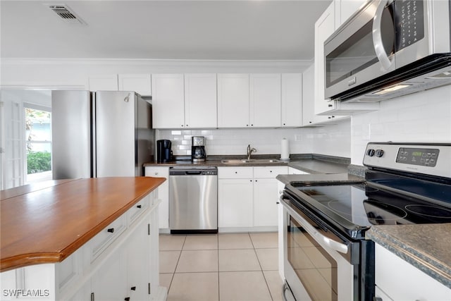 kitchen with backsplash, white cabinets, sink, light tile patterned floors, and stainless steel appliances