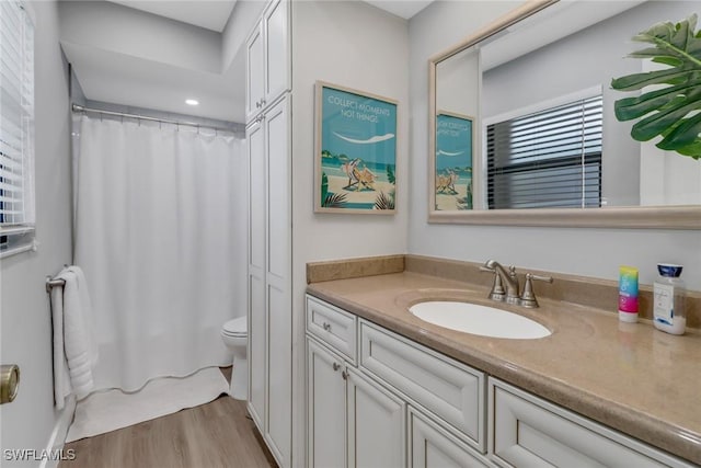 bathroom featuring walk in shower, toilet, vanity, and hardwood / wood-style flooring