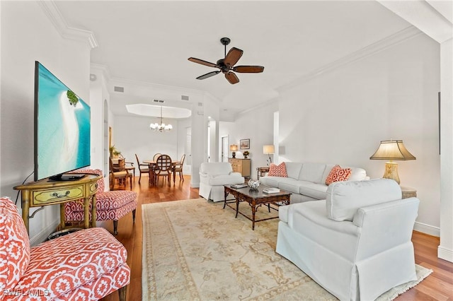 living room featuring wood-type flooring, ceiling fan with notable chandelier, and crown molding