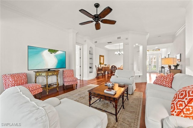 living room featuring wood-type flooring, ceiling fan with notable chandelier, and ornamental molding