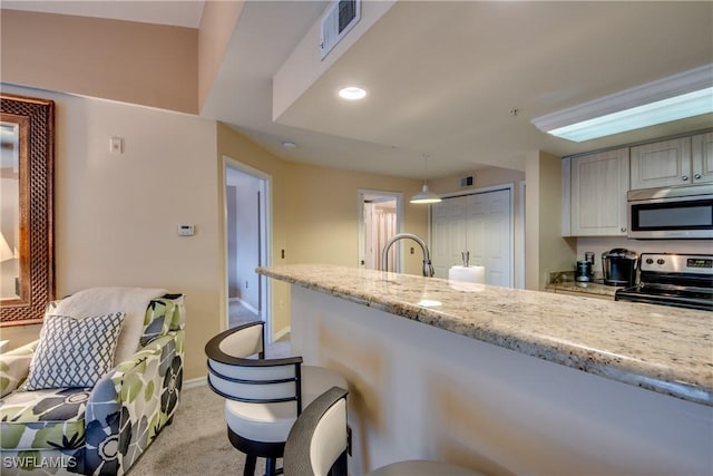 kitchen featuring light colored carpet, visible vents, appliances with stainless steel finishes, light stone countertops, and decorative light fixtures