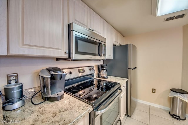 kitchen featuring light stone counters, light tile patterned floors, stainless steel appliances, visible vents, and baseboards