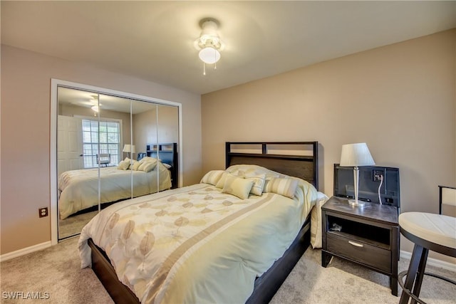 bedroom with baseboards, a closet, and light colored carpet