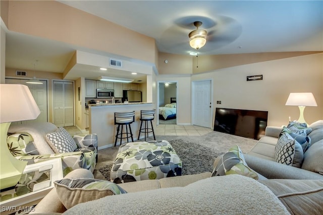 living area with visible vents, vaulted ceiling, light carpet, and light tile patterned flooring