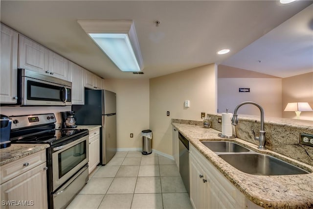 kitchen with white cabinets, light stone counters, stainless steel appliances, a sink, and light tile patterned flooring