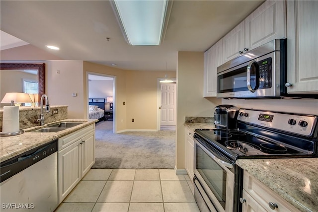 kitchen with stainless steel appliances, a sink, light stone countertops, and white cabinets