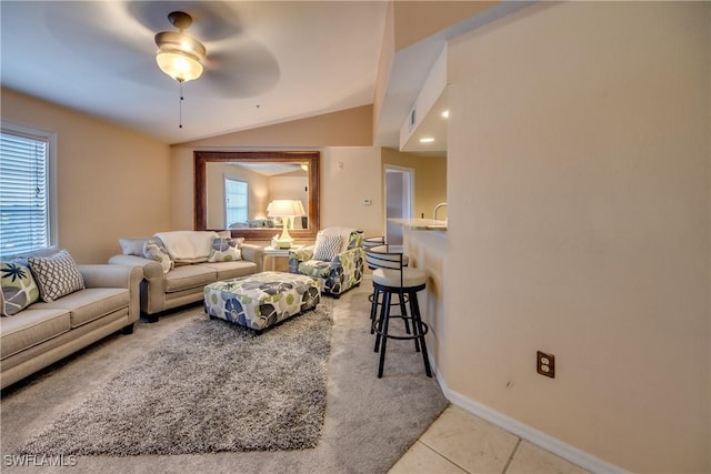 living room with lofted ceiling, light tile patterned floors, baseboards, and a ceiling fan