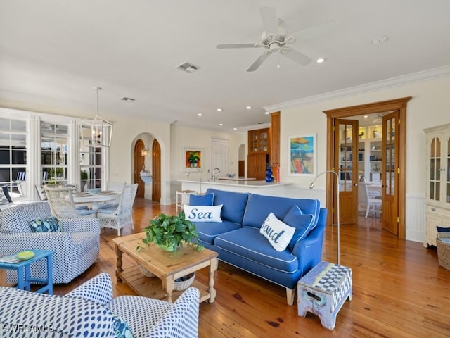 living room with light wood-type flooring, ceiling fan, crown molding, and sink