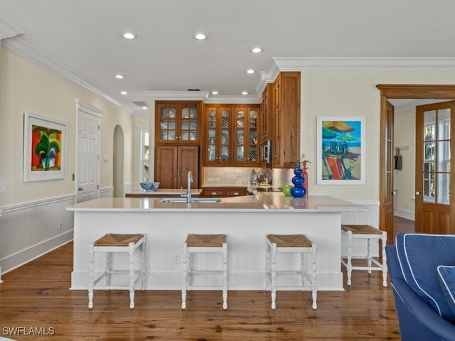 kitchen featuring a breakfast bar, dark hardwood / wood-style flooring, kitchen peninsula, and crown molding