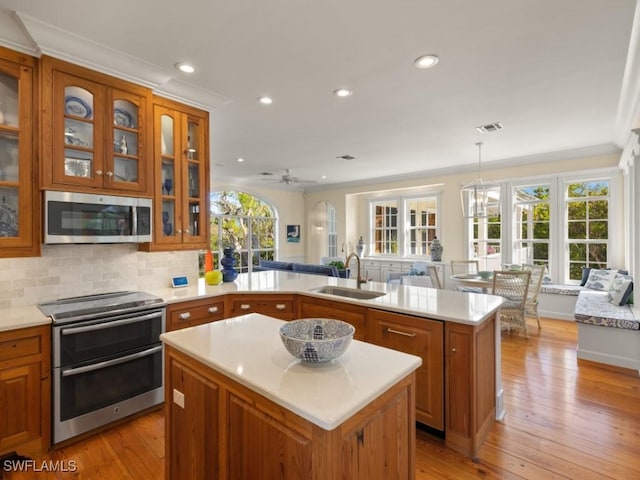 kitchen featuring hanging light fixtures, sink, stainless steel appliances, and a kitchen island with sink