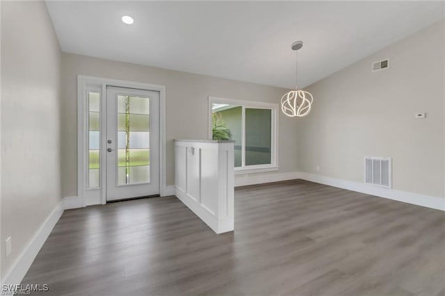 interior space with an inviting chandelier, dark hardwood / wood-style floors, and vaulted ceiling