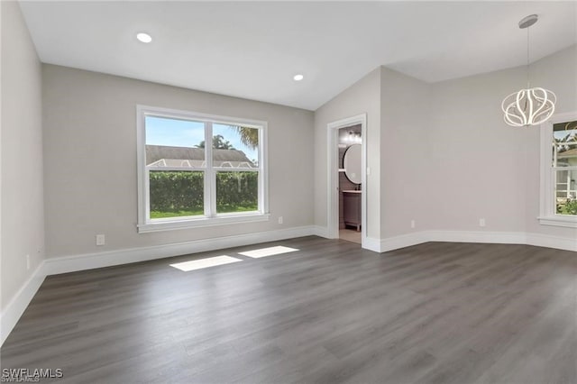 unfurnished room with dark hardwood / wood-style floors, lofted ceiling, and an inviting chandelier