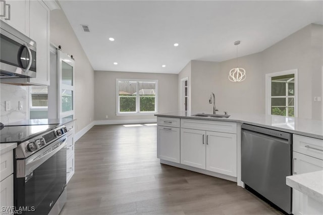 kitchen featuring hanging light fixtures, sink, light hardwood / wood-style flooring, appliances with stainless steel finishes, and white cabinetry