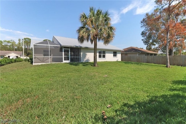 back of property with glass enclosure and a yard