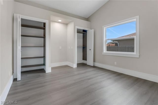 unfurnished bedroom with wood-type flooring and vaulted ceiling